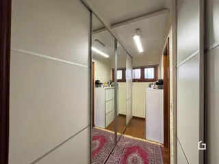 Hall de entrada com piso de madeira e espelho refletindo o interior da casa.