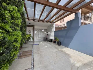 Vista externa da fachada de uma residência com vegetação exuberante.