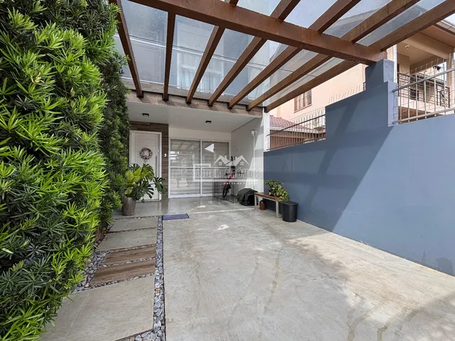 Vista externa da fachada de uma residência com vegetação exuberante.