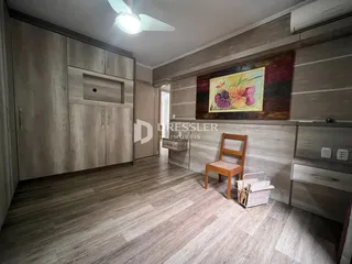 Ambiente interno de uma sala com piso de madeira e armários em tom claro.