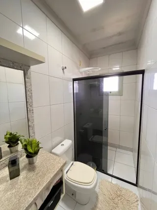 Foto de um banheiro com revestimento de azulejos brancos e box de vidro.