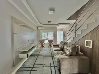 Vista de um corredor moderno com sala de estar e escadaria em um imóvel.