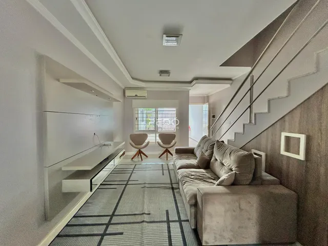 Vista de um corredor moderno com sala de estar e escadaria em um imóvel.