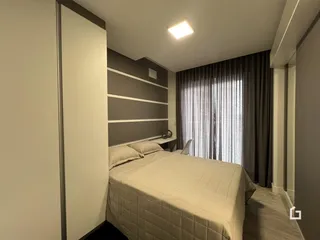Quarto com cama e cortinas em ambiente interno.