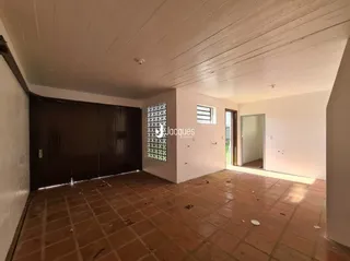 Interior de uma sala com piso de terracota e paredes brancas.