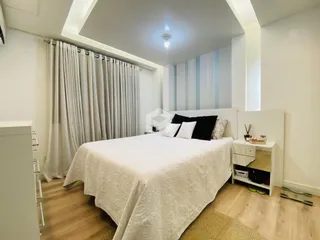 Quarto com cama e cortinas em ambiente claro.