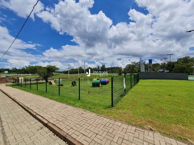Vista externa de um jardim com cerca e calçada.