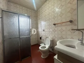 Interior de um banheiro com piso de cerâmica e paredes revestidas.