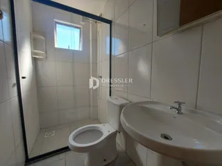 Foto interna de um banheiro com azulejos brancos e louças sanitárias.