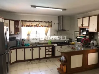 Uma cozinha com armários de madeira e bancada clara é visível na imagem.