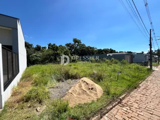 A foto mostra a fachada de uma residência com área verde e caminho de tijolos.