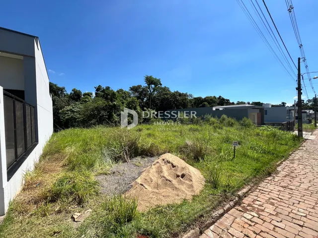 A foto mostra a fachada de uma residência com área verde e caminho de tijolos.