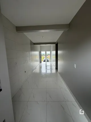 Foto de um corredor interno com piso de mármore branco.