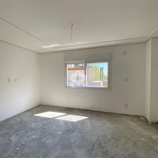 Imagem de um cômodo vazio com paredes brancas e piso de concreto.
