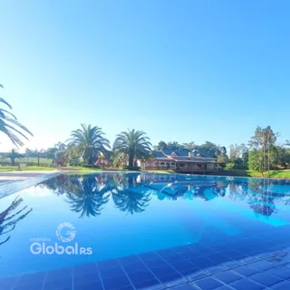 Foto da piscina externa refletindo o céu e a vegetação ao fundo da propriedade.