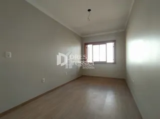 Um cômodo interno com piso de madeira clara e paredes brancas.