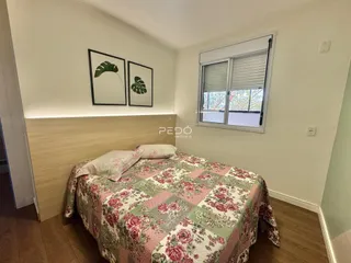 Quarto com cama decorada com edredom floral e painel de madeira.