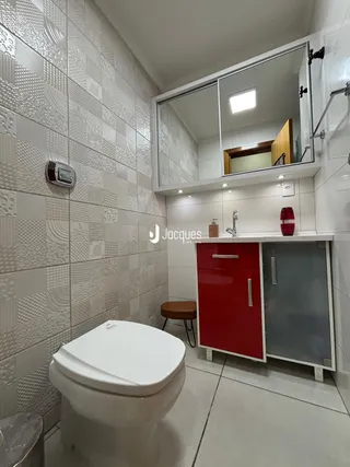 Foto interna de um banheiro com revestimento cerâmico branco e móveis vermelhos.