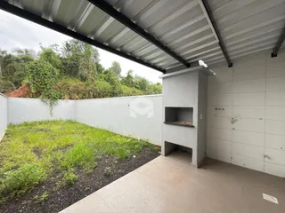 Vista externa de um quintal com vegetação ao lado de uma parede branca.