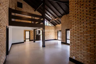 Interior de um espaço com paredes de tijolo aparente e estrutura de madeira.
