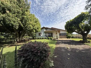 A fachada de uma casa em Lajeado, Brasil, cercada por árvores e gramado.