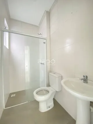 Foto de um banheiro interno com azulejos brancos e box de vidro.