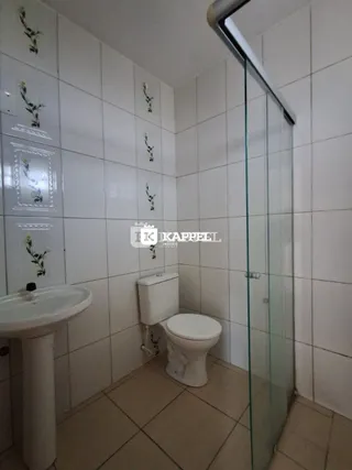 Foto de um banheiro com azulejos brancos e um box de vidro transparente.