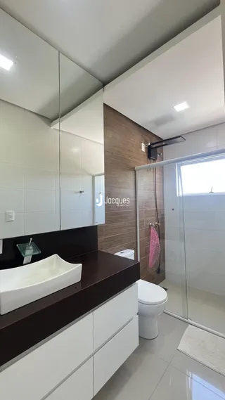 Interior de um banheiro moderno com bancada e box de vidro.