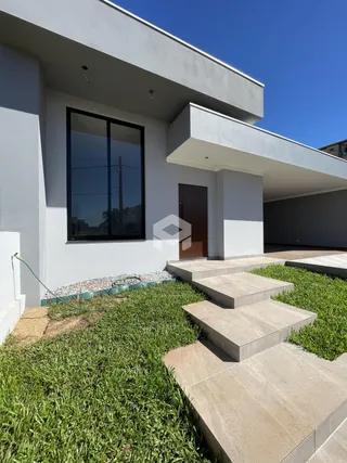 Fachada moderna de uma residência com jardim gramado e acesso em degraus de concreto.
