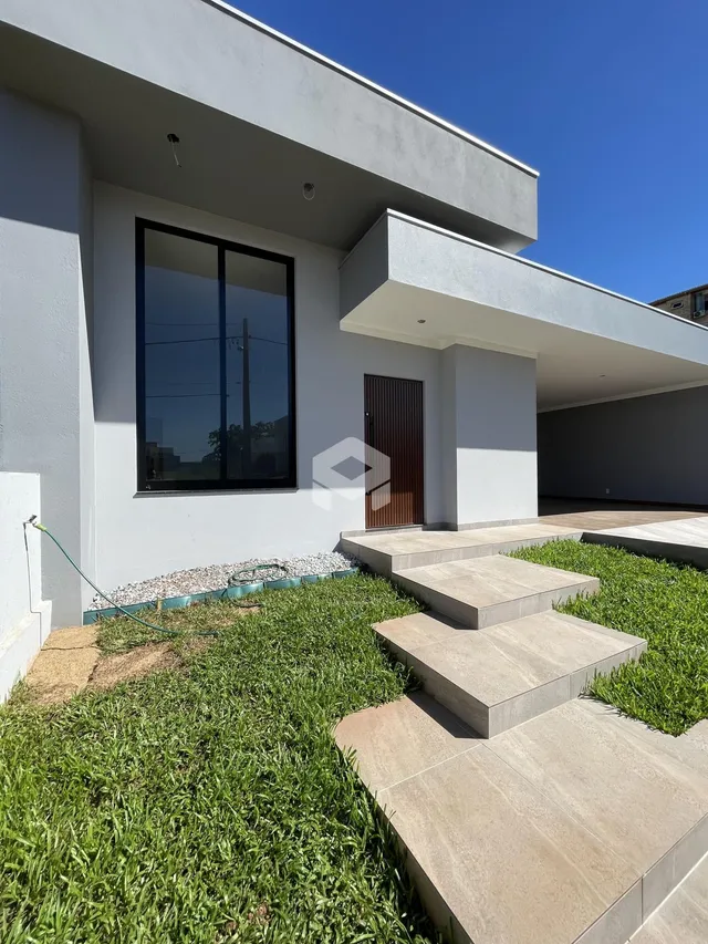 Fachada moderna de uma residência com jardim gramado e acesso em degraus de concreto.