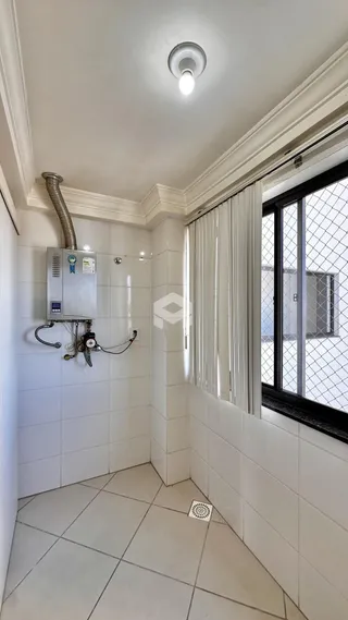 Corredor com paredes de azulejo branco e janela.