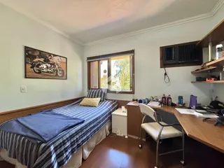 Quarto com cama e janela de madeira no interior da residência.