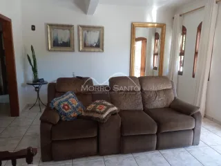 Sala de estar com um sofá grande de couro marrom e paredes brancas.