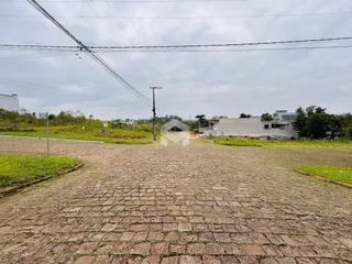 A foto mostra a entrada de uma propriedade com pavimento de paralelepípedos.