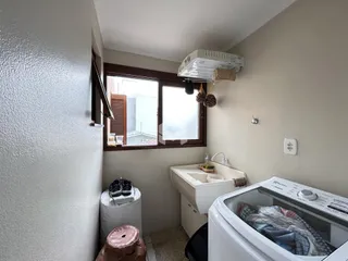 Interior de um cômodo com janela e máquina de lavar roupa.