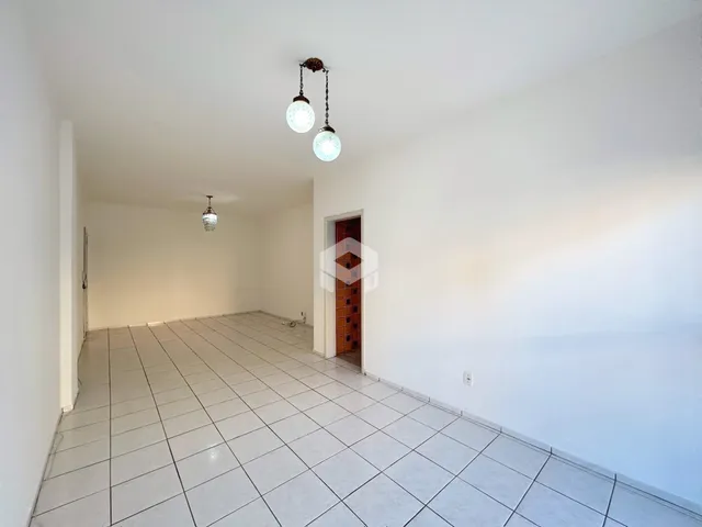 Corredor longo com piso de cerâmica claro na residência.