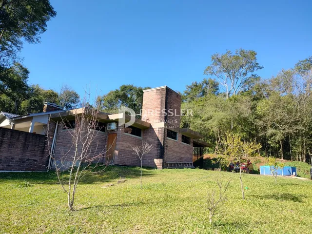 A fachada de uma casa de tijolos em Lajeado, Brasil, cercada por vegetação.