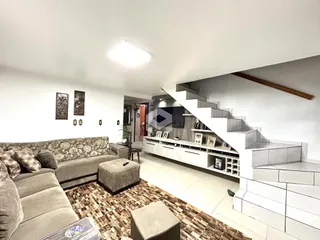Sala de estar com sofá e escadaria em um apartamento.