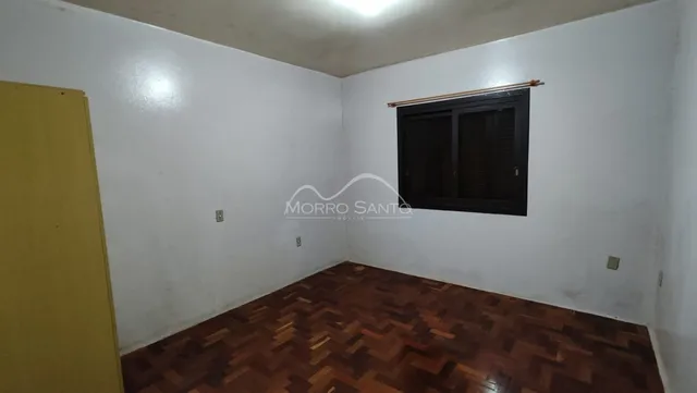 Este é um cômodo interno com piso de madeira escura e paredes brancas.