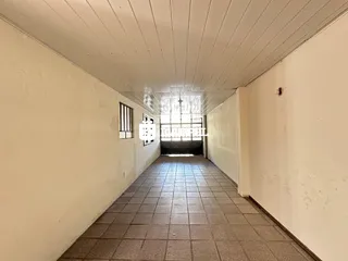 Foto de um corredor interno com piso de cerâmica e paredes brancas.
