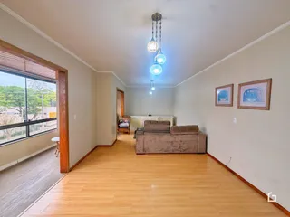 Sala de estar com piso de madeira clara e grande janela.