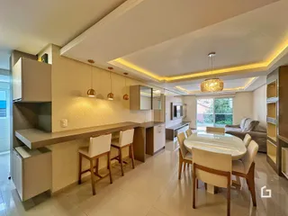 Interior de uma sala de estar e cozinha moderna com iluminação embutida.