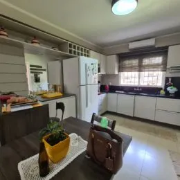 Foto interna de uma cozinha com armários brancos e bancadas escuras.