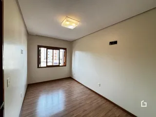Vista interna de uma sala com piso de madeira e janela.