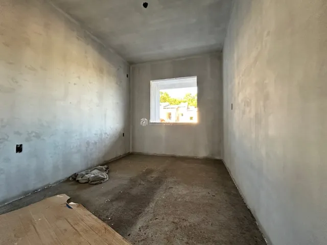 Vista interna de um corredor com paredes brancas e piso de concreto.