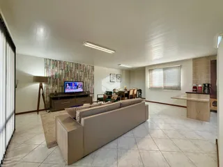 Sala de estar com piso de cerâmica e sofá bege.