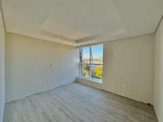 Ambiente interno de uma sala com piso cru e grande janela com vista.