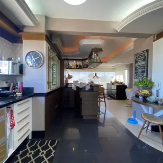Imagem de uma cozinha moderna com ilha e área de jantar em um imóvel no Brasil.