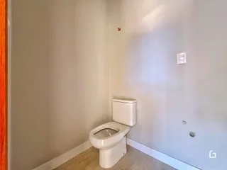 Foto de uma parede interna mostrando um vaso sanitário branco.
