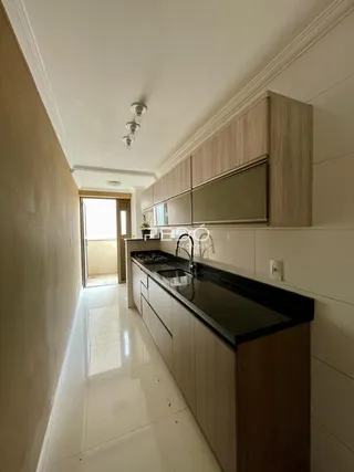 Corredor interno de uma residência com revestimento claro e armários de madeira.
